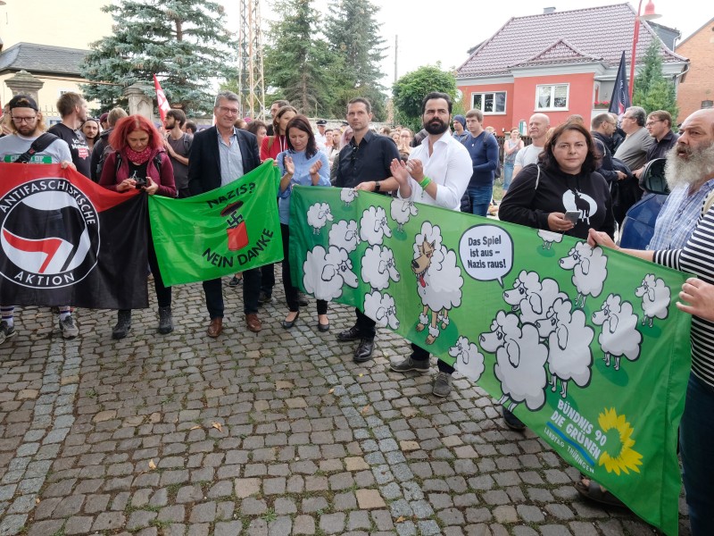 Teilnehmer einer Protestkundgebung stehen mit Transparenten in der Gemeinde. 