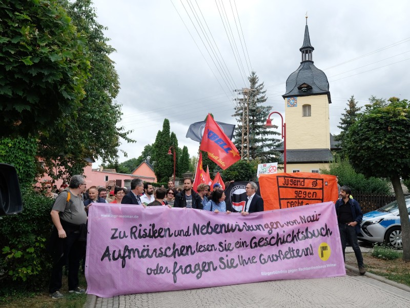 Teilnehmer einer Protestkundgebung gehen mit Transparenten durch die Gemeinde. 