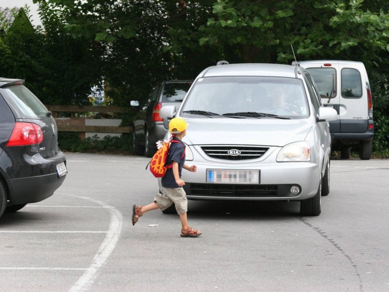 Kleiner Junge rennt über die Straße vor ein Auto