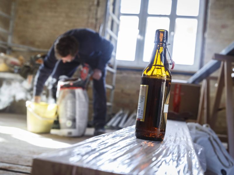 Bauarbeiter mit Bierflasche im Vordergrund
