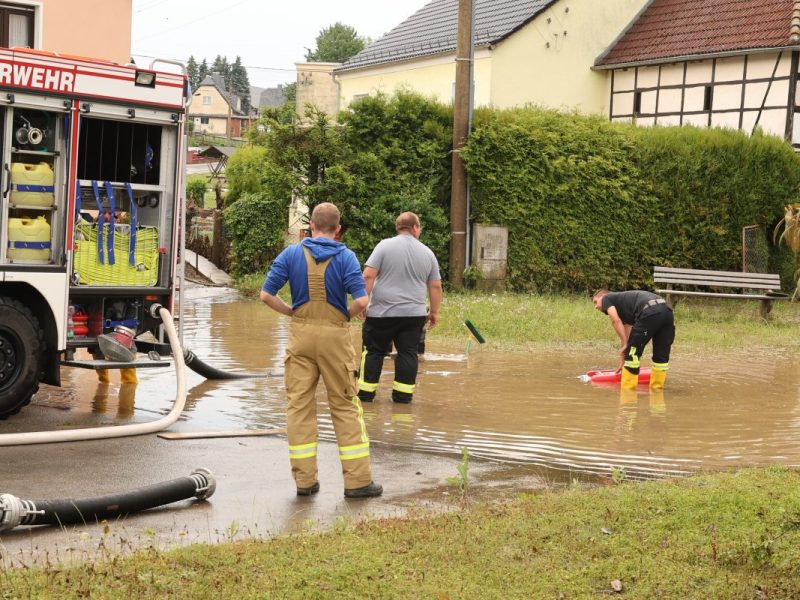 Nach einem Starkregen pumpen Einsatzkräfte der Feuerwehr auf dem Dorfplatz von Hilbersdorf das Wasser ab. Nach heftigen Gewittern kam es in Ostthüringen zu zahlreichen Überschwemmungen.