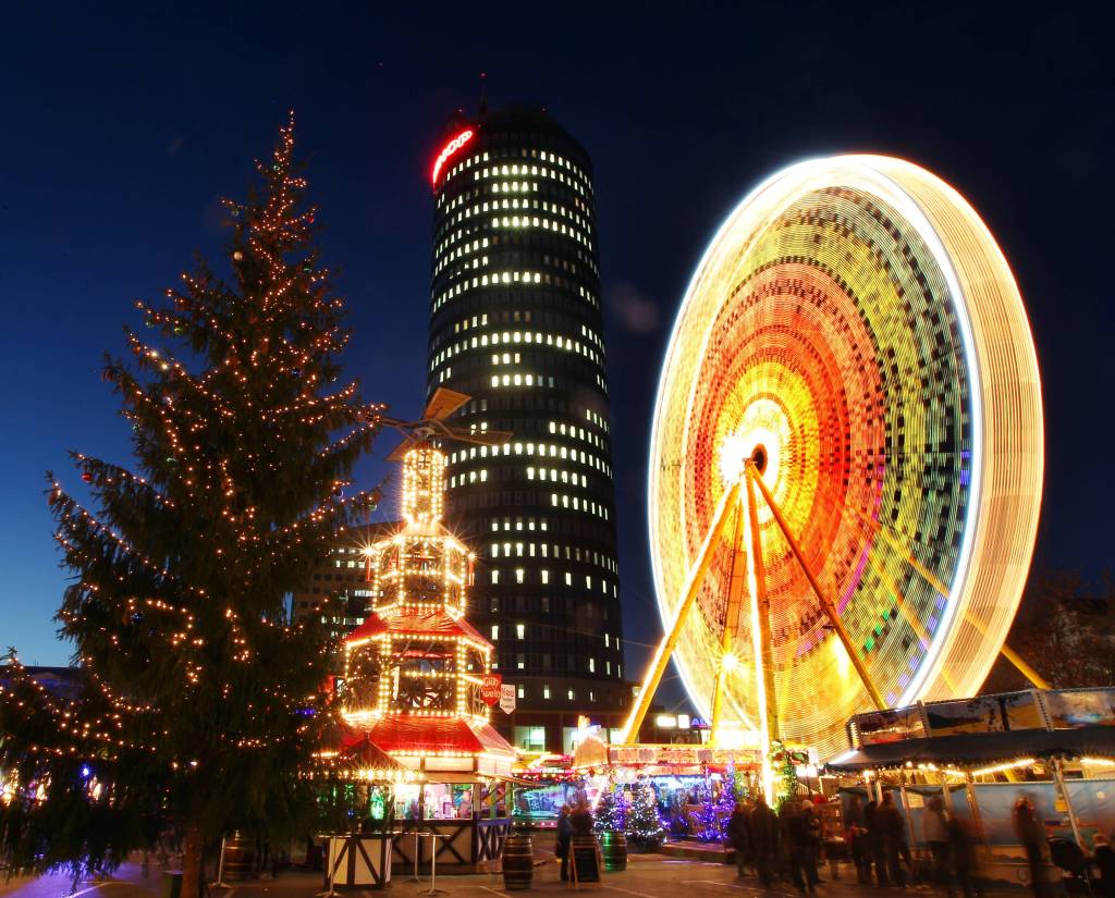 Weihnachtsmarkt mit buntem Riesenrad und Weihnachtspyramide. 