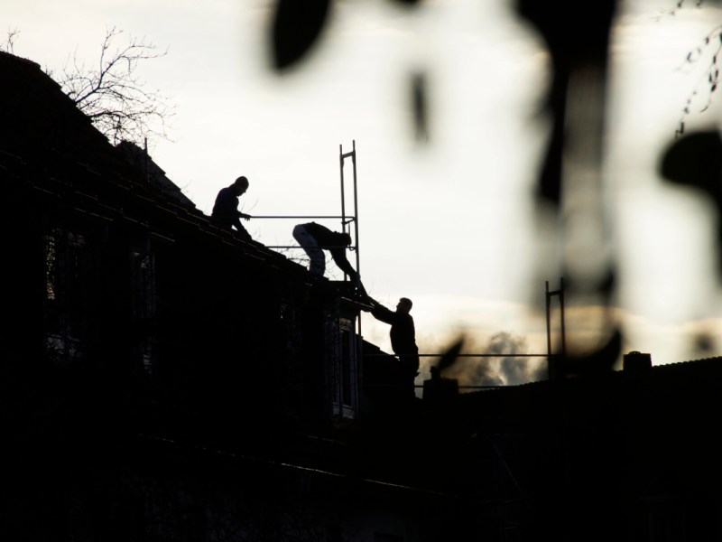 Schatten von Bauarbeitern auf dem Dach