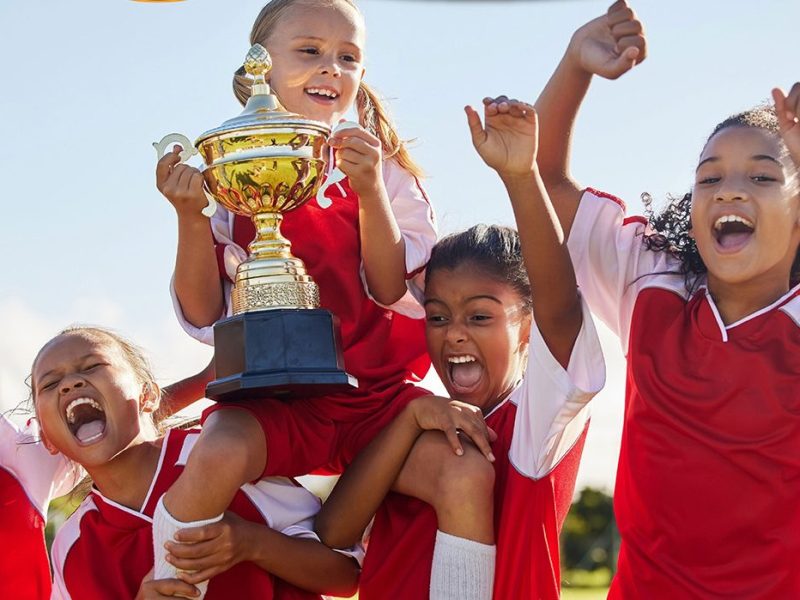Junge Fußballerinnen freuen sich und halten einen Pokal in die Höhe (Symbolbild)